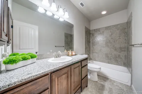 a bathroom with a granite countertop sink a toilet a mirror and bathtub