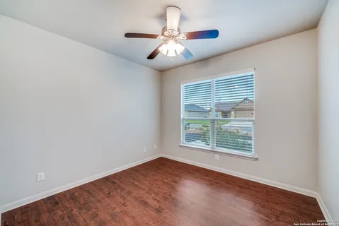 an empty room with wooden floor chandelier fan and windows