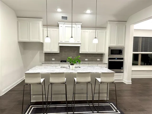 a kitchen with kitchen island granite countertop a stove a sink and a refrigerator