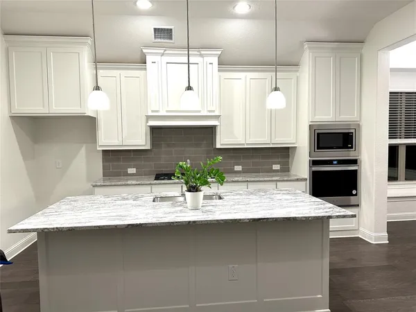 a kitchen with stainless steel appliances white cabinets a sink and a stove
