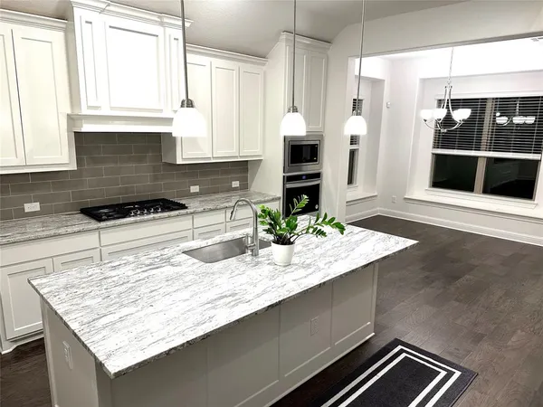 a kitchen with kitchen island granite countertop a stove and a sink