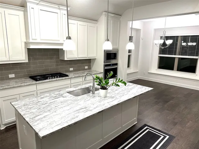 a kitchen with kitchen island granite countertop a stove and a sink
