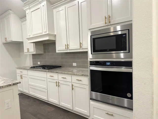 a kitchen with stainless steel appliances granite countertop white cabinets and a stove a oven with white countertops