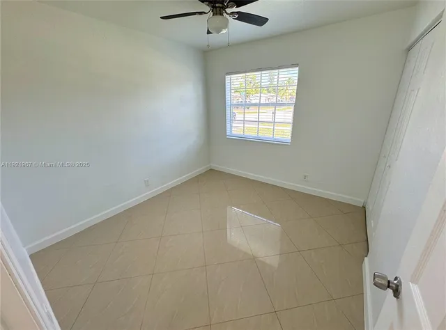 an empty room with a window and a ceiling fan