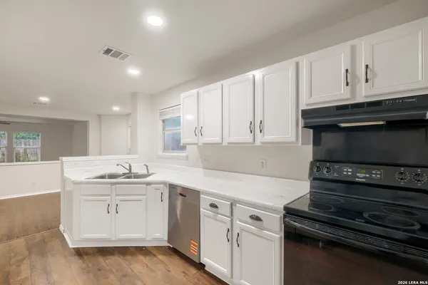 a kitchen with granite countertop white cabinets and black appliances