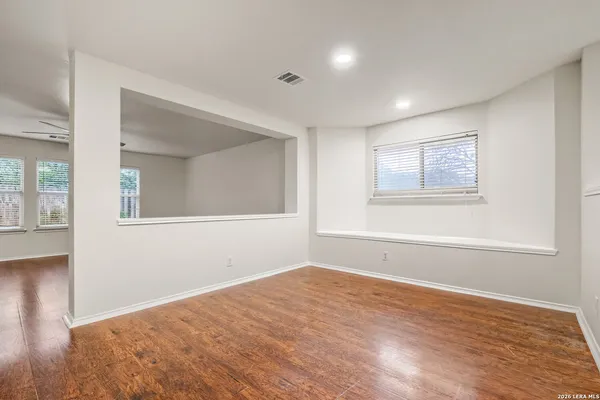 a view of empty room with wooden floor and fan