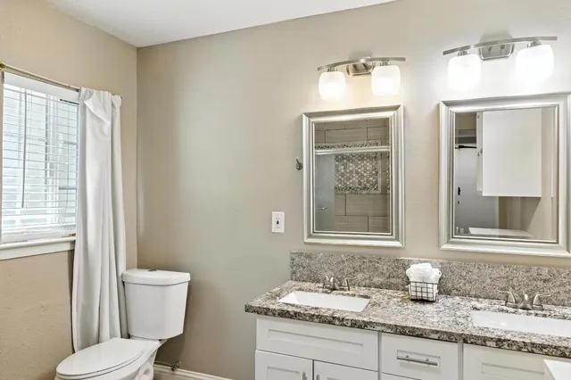 a bathroom with a granite countertop sink toilet and mirror