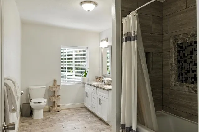 a bathroom with a granite countertop toilet a sink and a bathtub