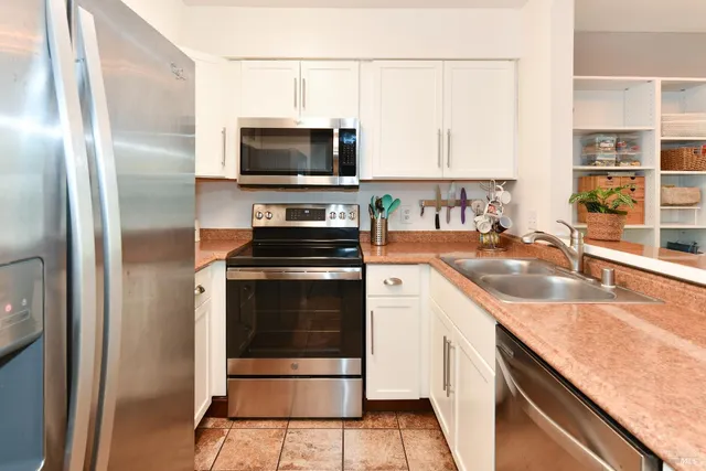 a kitchen with stainless steel appliances granite countertop a sink a stove and a refrigerator