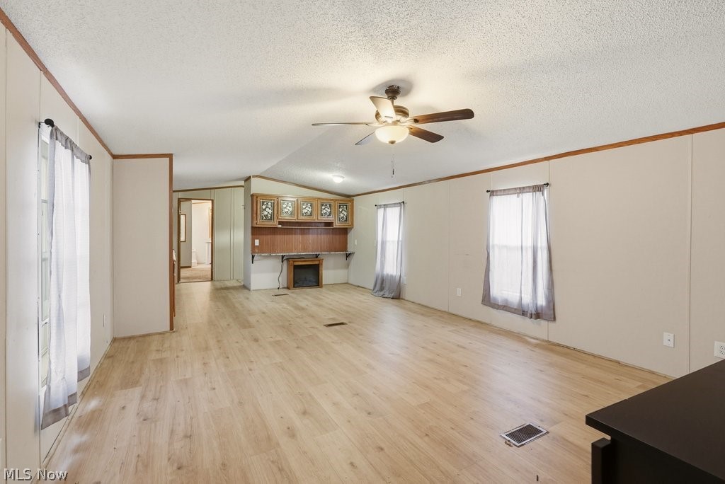 6507 Robby Lane Ravenna, OH 44266 - Photo 5 of 25 Unfurnished living room featuring ornamental molding, a ceiling fan, light wood-style floors, and a fireplace