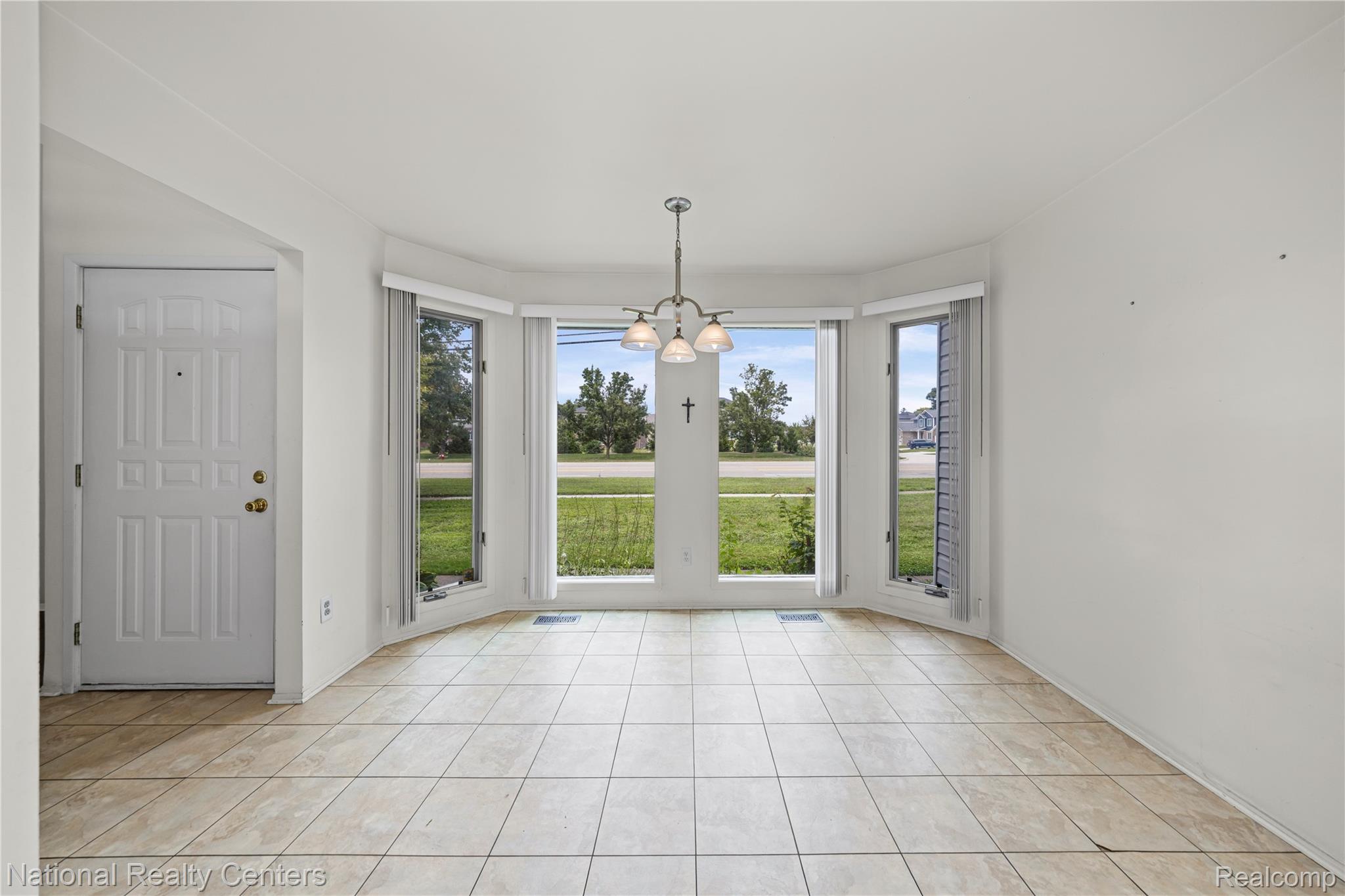 5274 East 14 Mile Road Warren, MI 48092 - Photo 8 of 31 Bay window with three large windows, a multi-light chandelier, and tile flooring