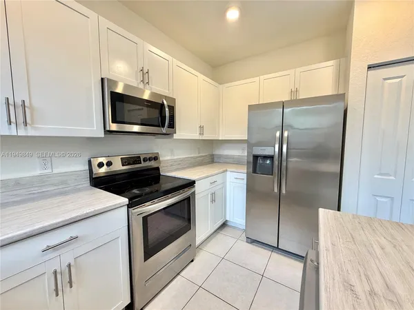 a kitchen with white cabinets stainless steel appliances and a counter top space