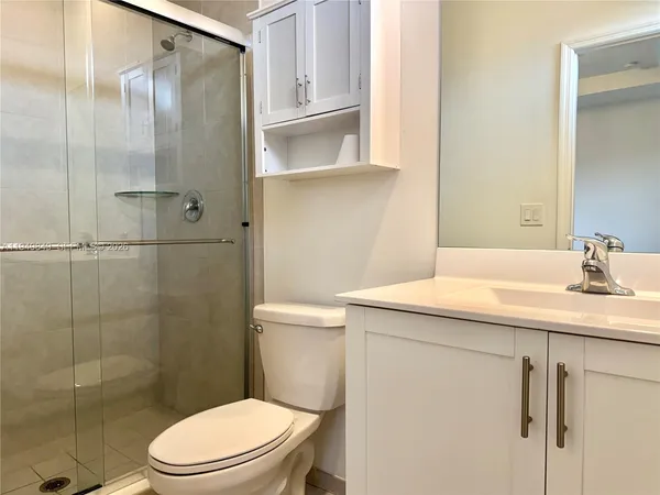 a bathroom with a granite countertop sink a toilet and shower