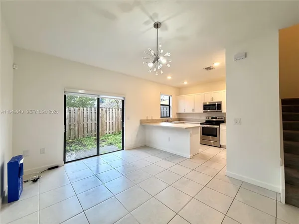 a large white kitchen with a stove a sink dishwasher and a refrigerator with wooden floor