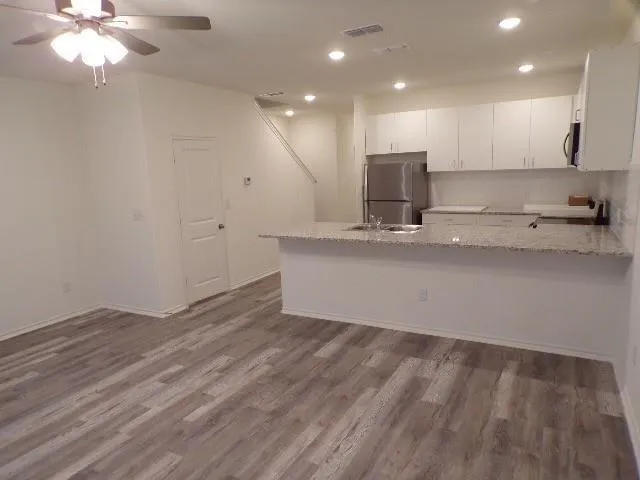a view of kitchen with granite countertop cabinets and refrigerator