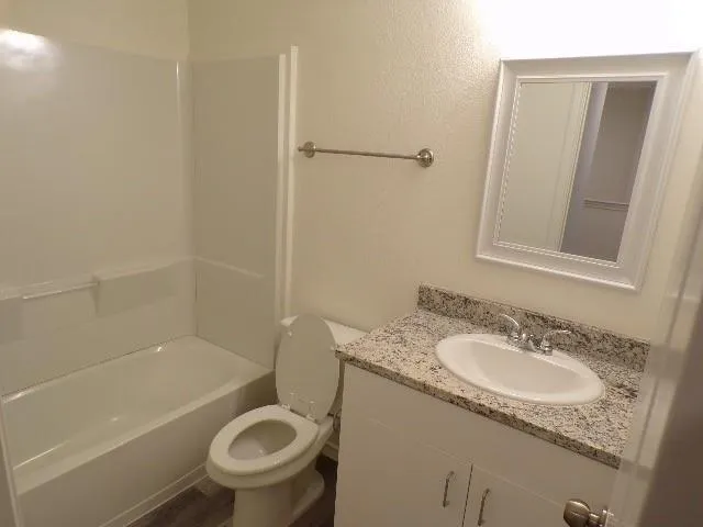 a bathroom with a granite countertop toilet a sink and bathtub