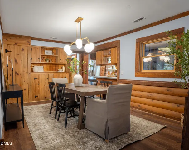 an empty room with wooden floor chandelier and windows
