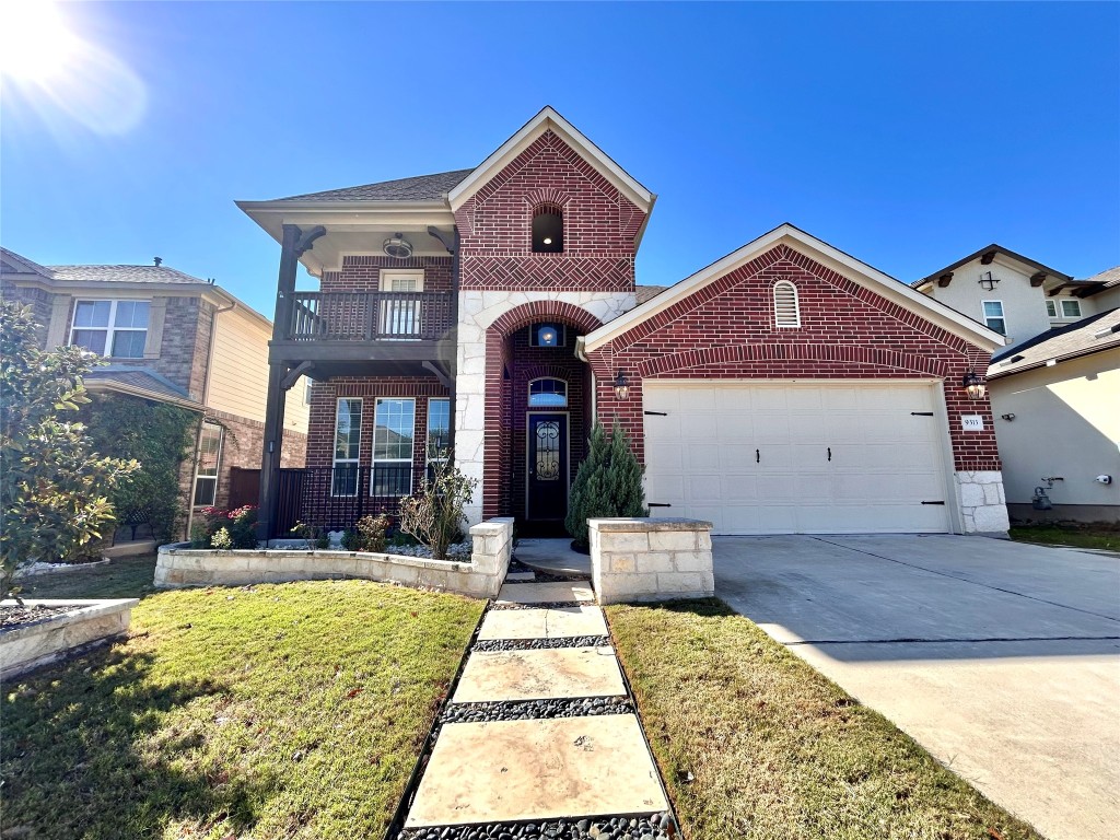 View of front of property with brick siding, concrete driveway, a front yard, a balcony, and a garage