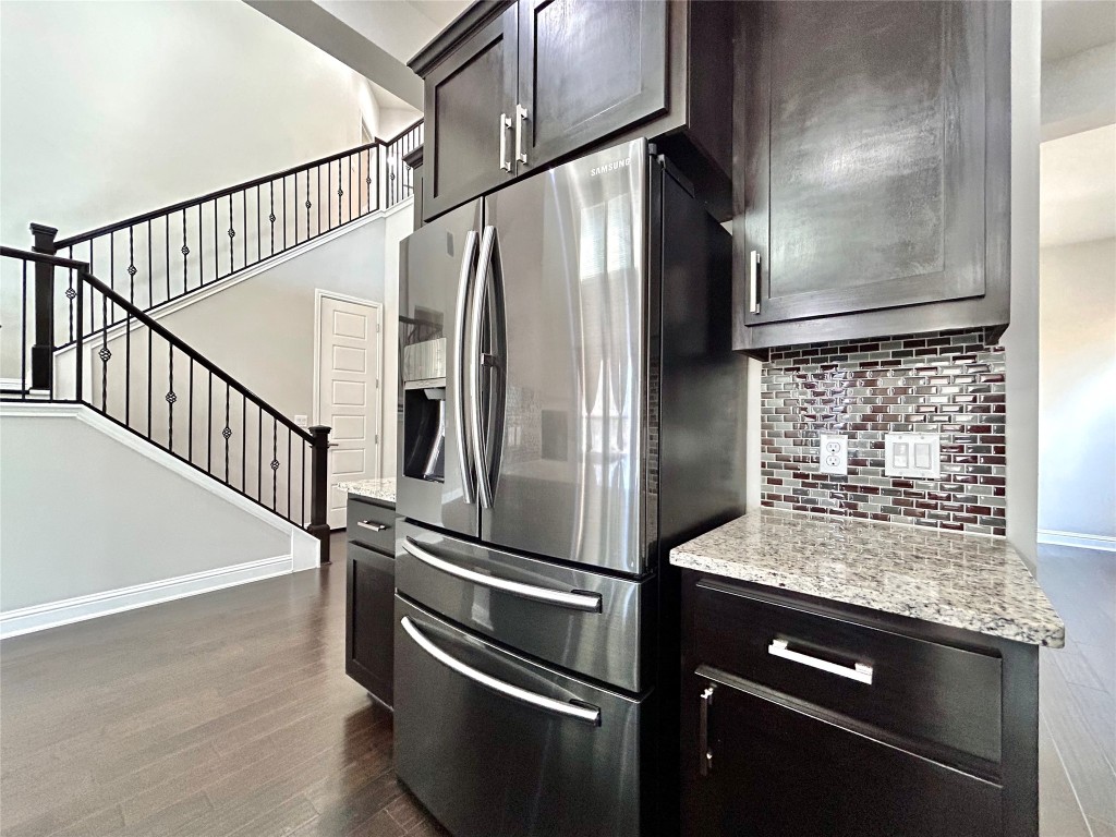 9313 Kyles Stake Road Austin, TX 78717 - Photo 11 of 40 Kitchen with stainless steel refrigerator with ice dispenser, light stone counters, dark wood-type flooring, and backsplash