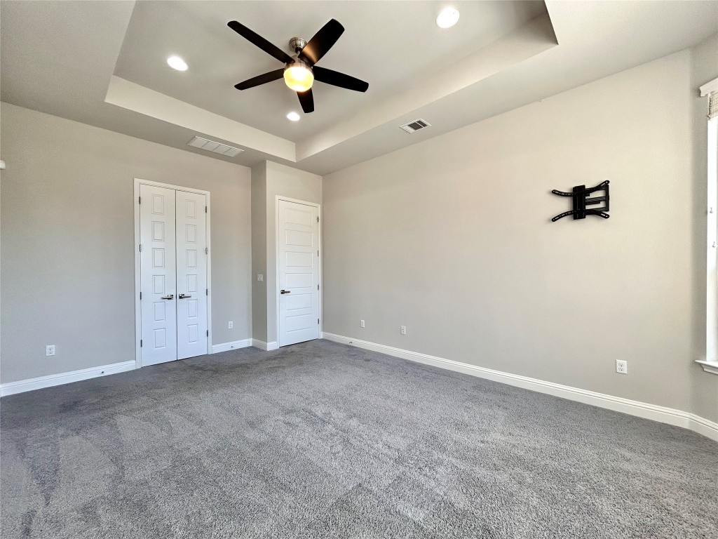 9313 Kyles Stake Road Austin, TX 78717 - Photo 17 of 40 Unfurnished bedroom featuring a tray ceiling, recessed lighting, dark colored carpet, and ceiling fan