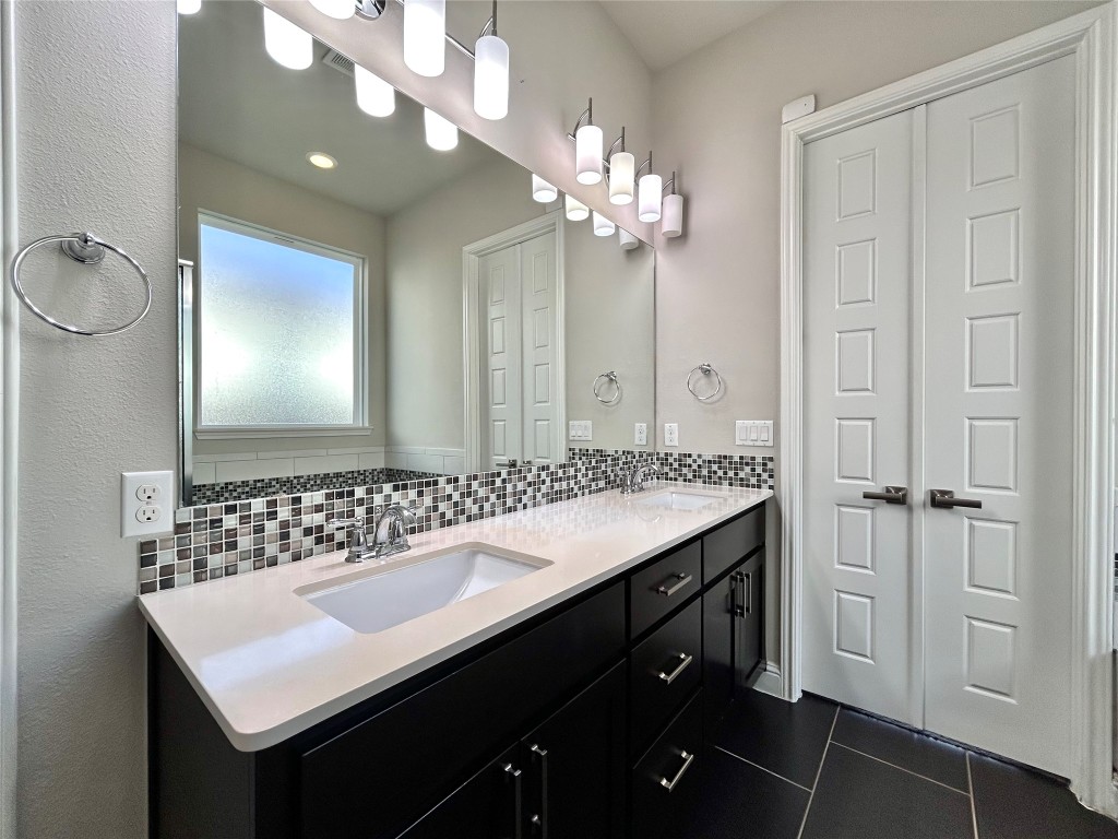 9313 Kyles Stake Road Austin, TX 78717 - Photo 18 of 40 Full bathroom featuring double vanity, tasteful backsplash, and dark tile patterned floors