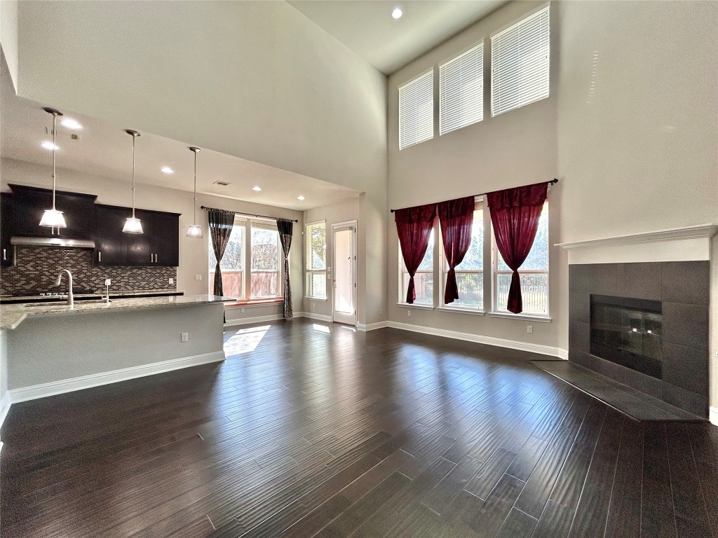 9313 Kyles Stake Road Austin, TX 78717 - Photo 5 of 40 Unfurnished living room with dark wood finished floors, a fireplace, recessed lighting, and a towering ceiling