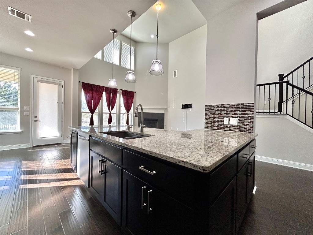 9313 Kyles Stake Road Austin, TX 78717 - Photo 7 of 40 Kitchen with dark cabinetry, pendant lighting, tasteful backsplash, light stone counters, and healthy amount of natural light