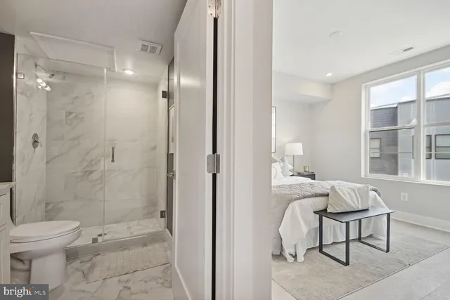 a spacious bathroom with a granite countertop sink toilet a mirror and a shower