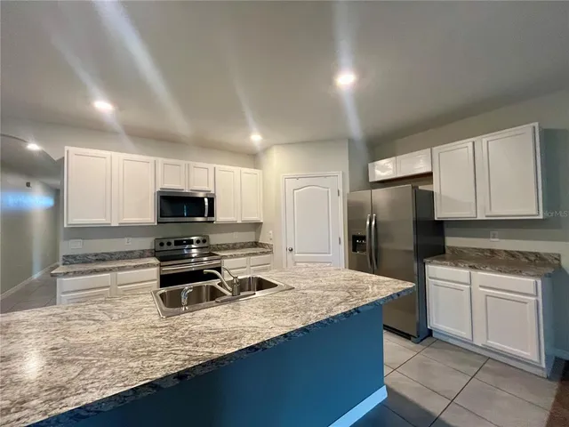 a kitchen with stainless steel appliances a sink a stove a microwave a refrigerator and cabinets