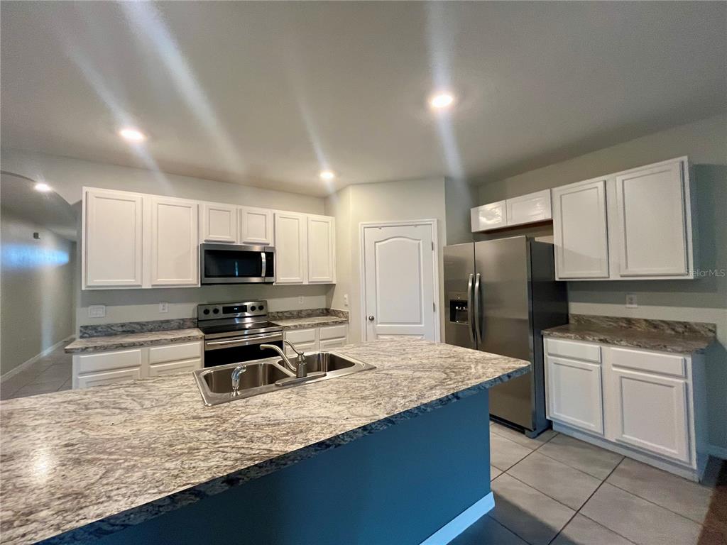 531 Auburn Grove Terrace Auburndale, FL 33823 - Photo 7 of 26 a kitchen with stainless steel appliances a sink a stove a microwave a refrigerator and cabinets