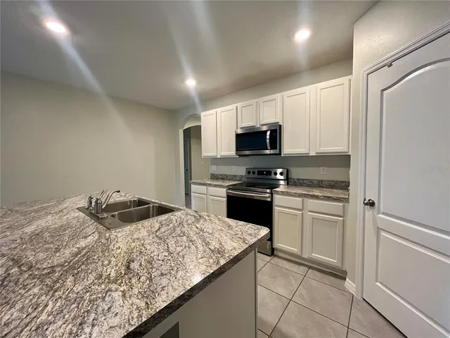 a kitchen with granite countertop a sink stove and refrigerator