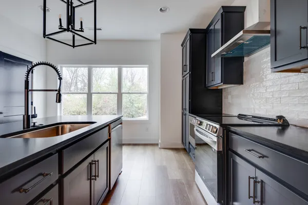 a kitchen with granite countertop a stove a sink and a microwave