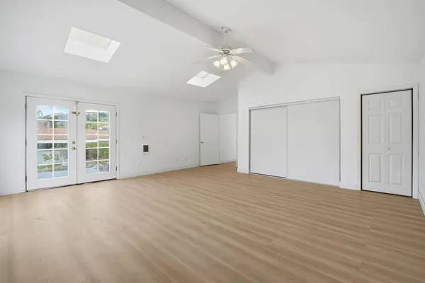 a view of an empty room with wooden floor and a window