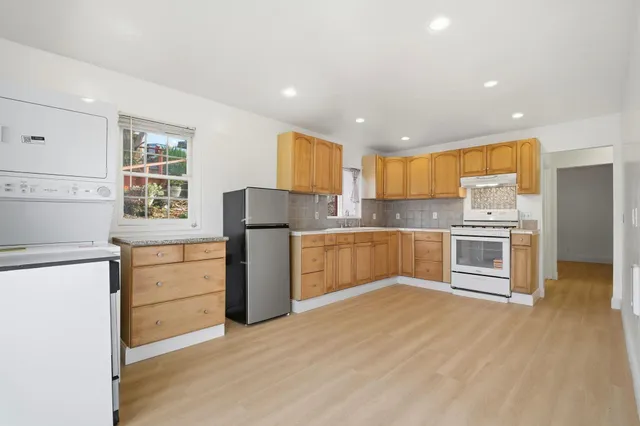 a kitchen with granite countertop a refrigerator cabinets and wooden floor