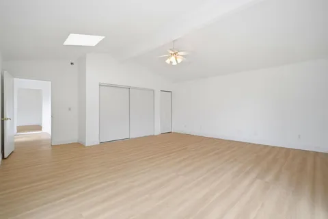 a view of empty room with wooden floor and ceiling fan