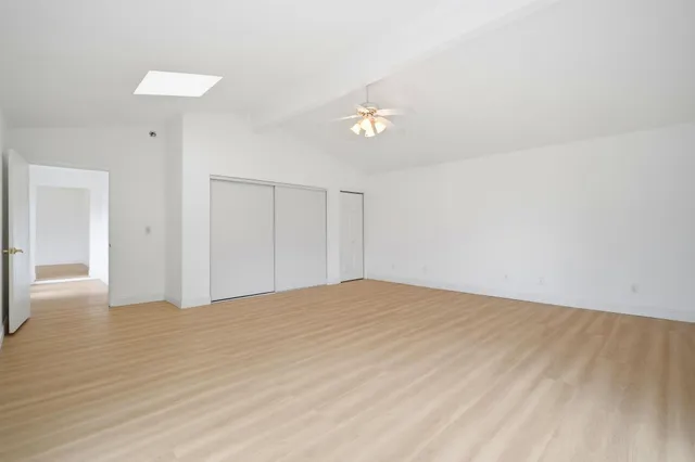 a view of empty room with wooden floor and ceiling fan