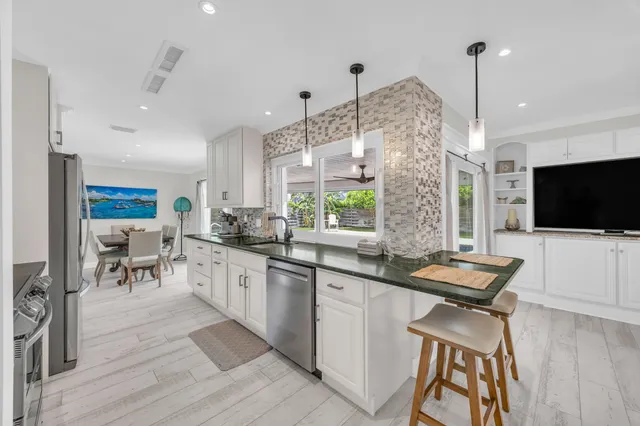 a kitchen with stainless steel appliances granite countertop a stove top oven a sink a dining table and chairs with wooden floor