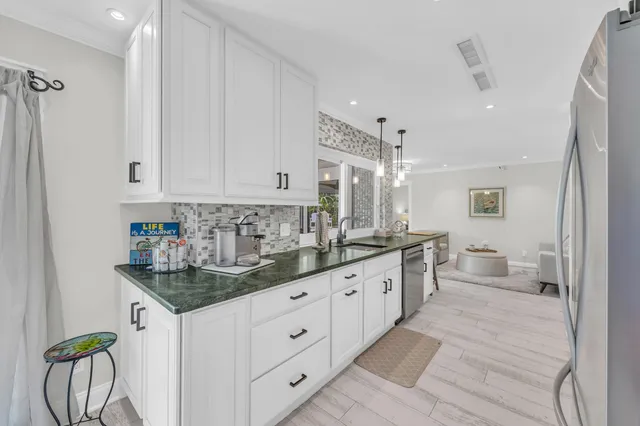 a large white kitchen with a lot of counter space and wooden floor
