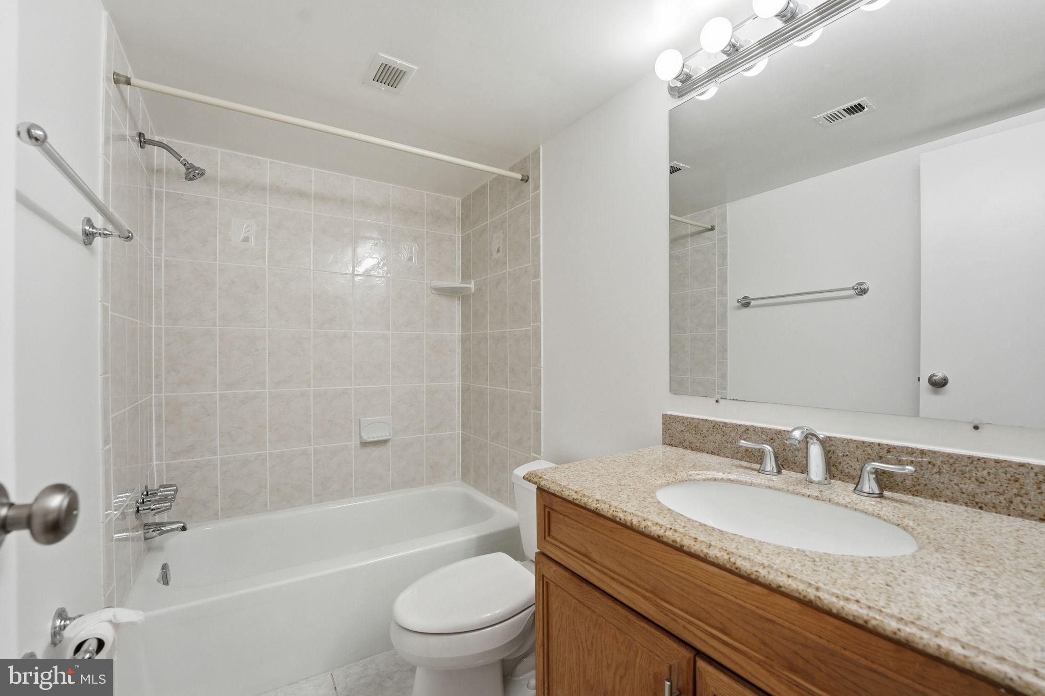 2817 Jermantown Road, Unit 107 Oakton, VA 22124 - Photo 16 of 28 a bathroom with a granite countertop sink a toilet and shower