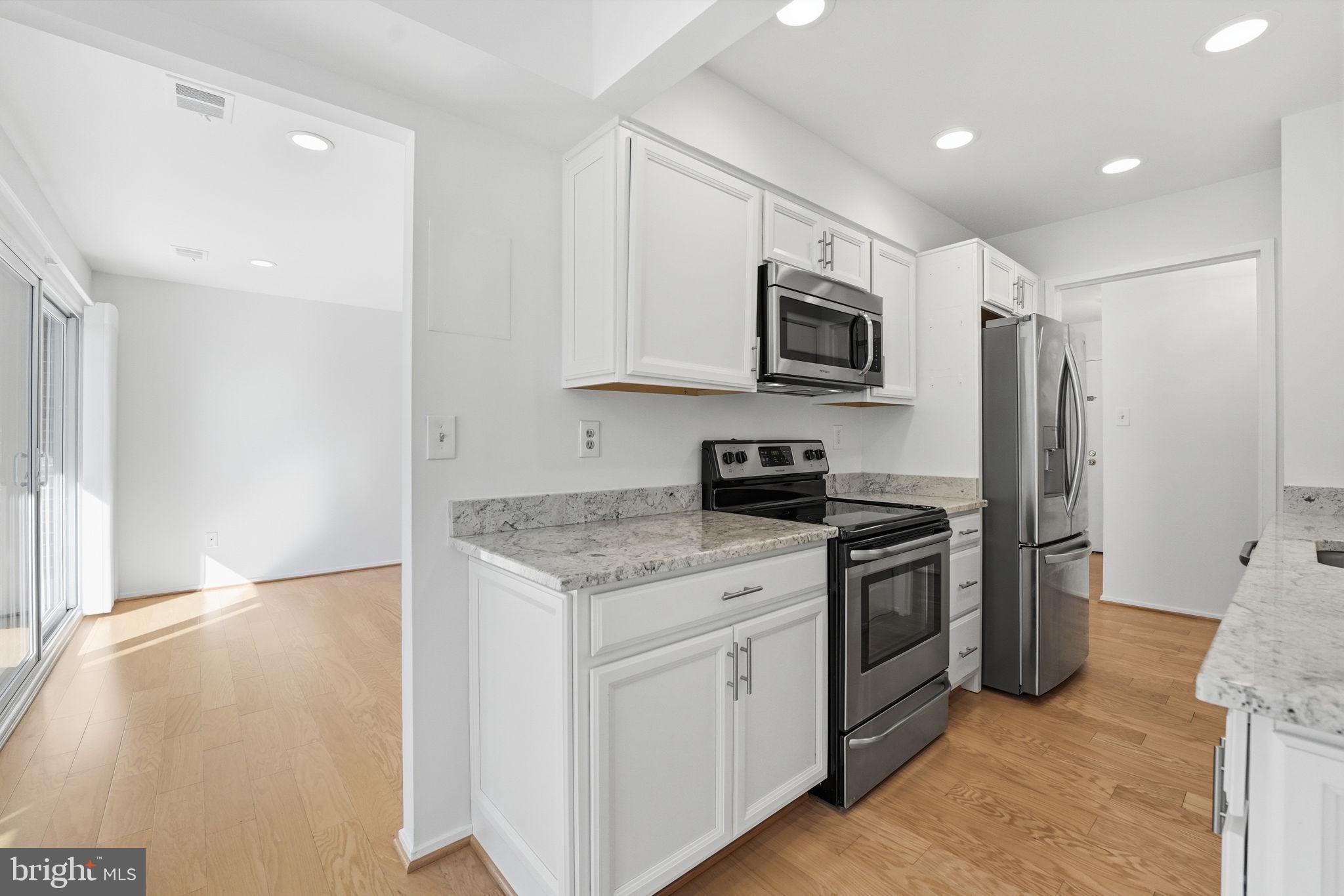 2817 Jermantown Road, Unit 107 Oakton, VA 22124 - Photo 5 of 28 a kitchen with stainless steel appliances granite countertop a stove a refrigerator and a microwave