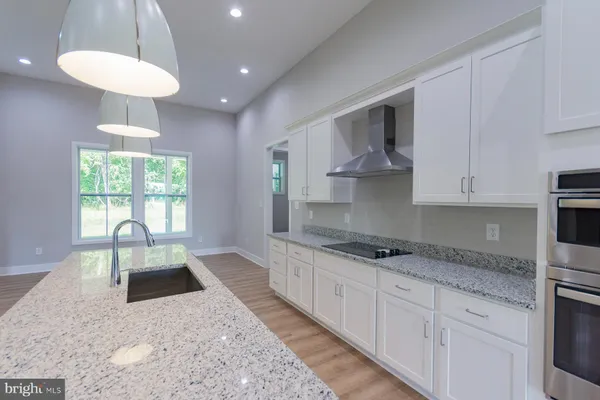 a large kitchen with granite countertop a sink a counter space appliances and cabinets