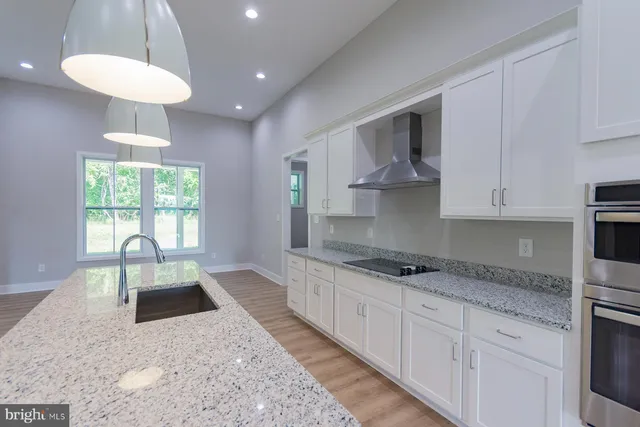 a large kitchen with granite countertop a sink a counter space appliances and cabinets