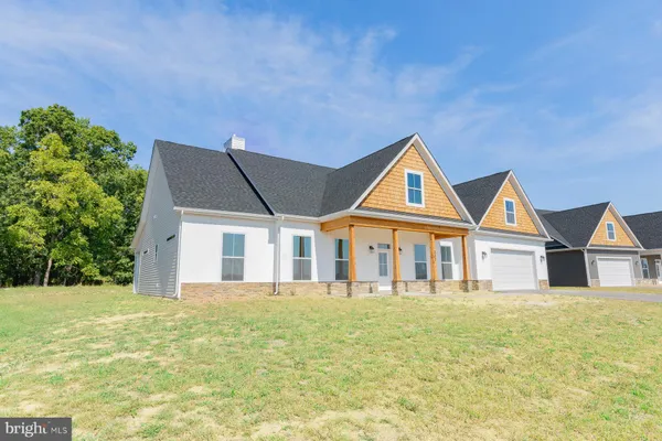a front view of house with yard and trees in the background