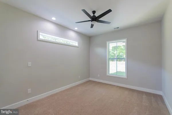 an empty room with ceiling fan and window