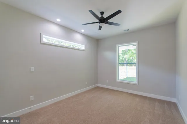 an empty room with ceiling fan and window