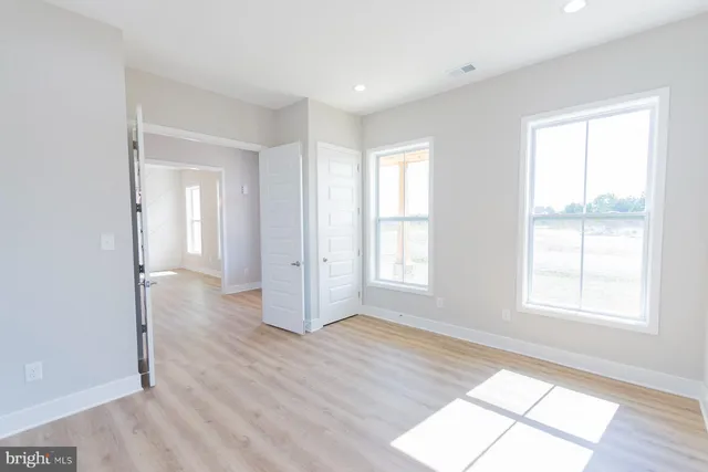an empty room with wooden floor and windows