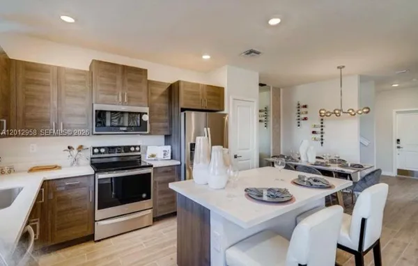 a kitchen with stainless steel appliances kitchen island granite countertop a stove a sink a refrigerator and white cabinets