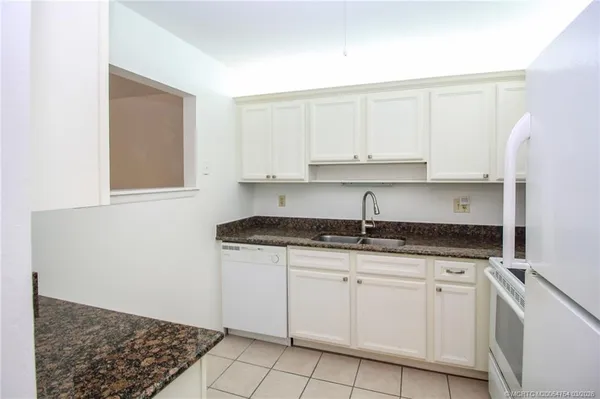 a kitchen with granite countertop white cabinets and white appliances