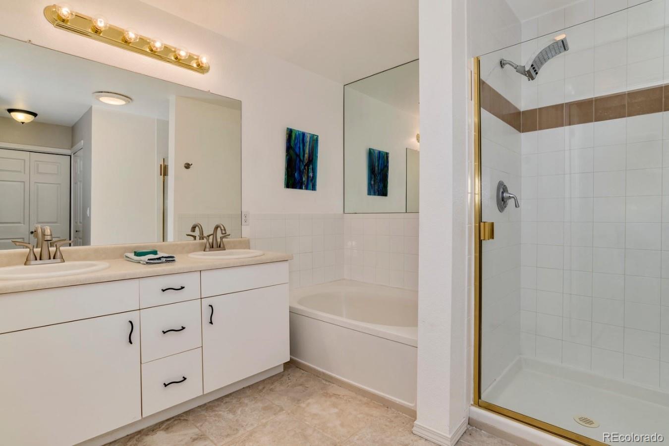 6486 Silver Mesa Drive, Unit B Highlands Ranch, CO 80130 - Photo 17 of 29 a bathroom with a double vanity sink a mirror a bathtub and shower