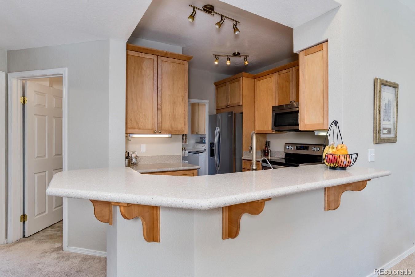 6486 Silver Mesa Drive, Unit B Highlands Ranch, CO 80130 - Photo 8 of 29 a kitchen with kitchen island a sink appliances and cabinets